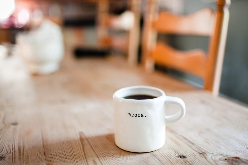 Photo of a mug of coffee with "BEGIN." written on the side