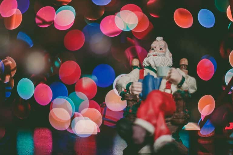 Closeup photo of lights on a christmas tree with a santa tree decoration in the foreground