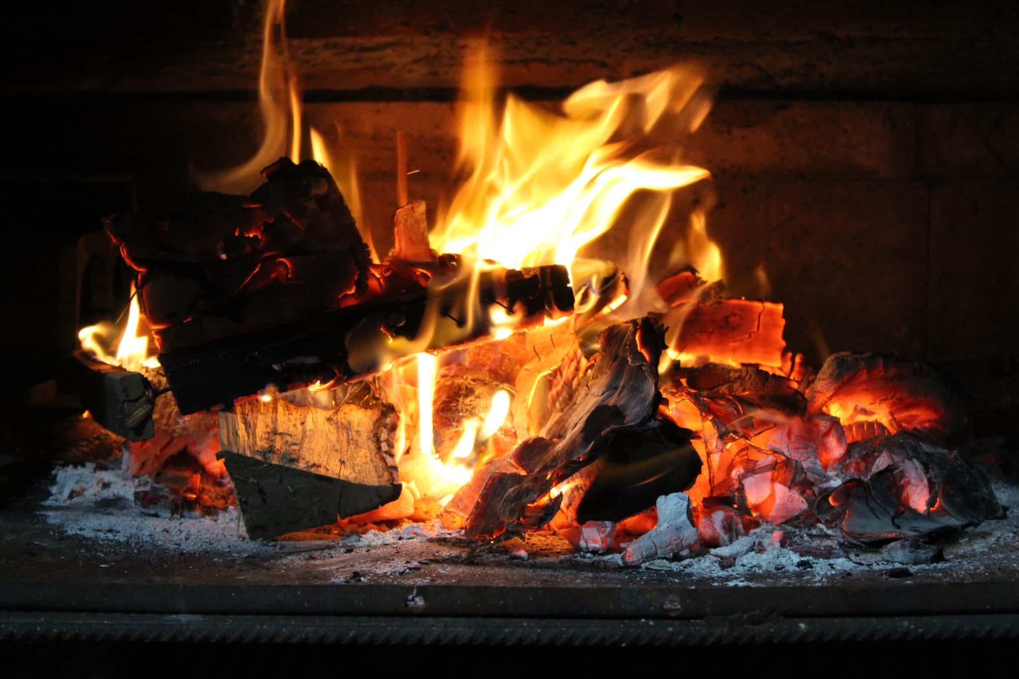 Photograph of a glowing log fire burning in a fire place
