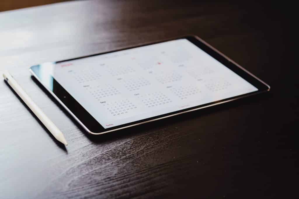 Photo of tablet sitting on desk with calendar app on screen