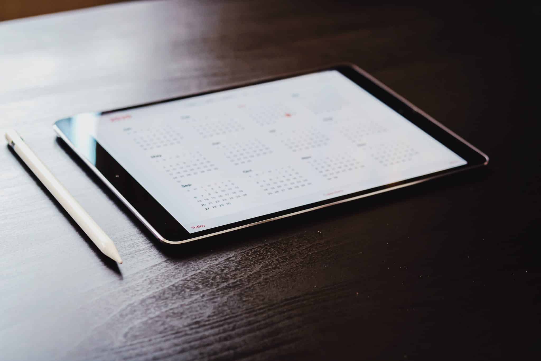 Photo of tablet sitting on desk with calendar app on screen