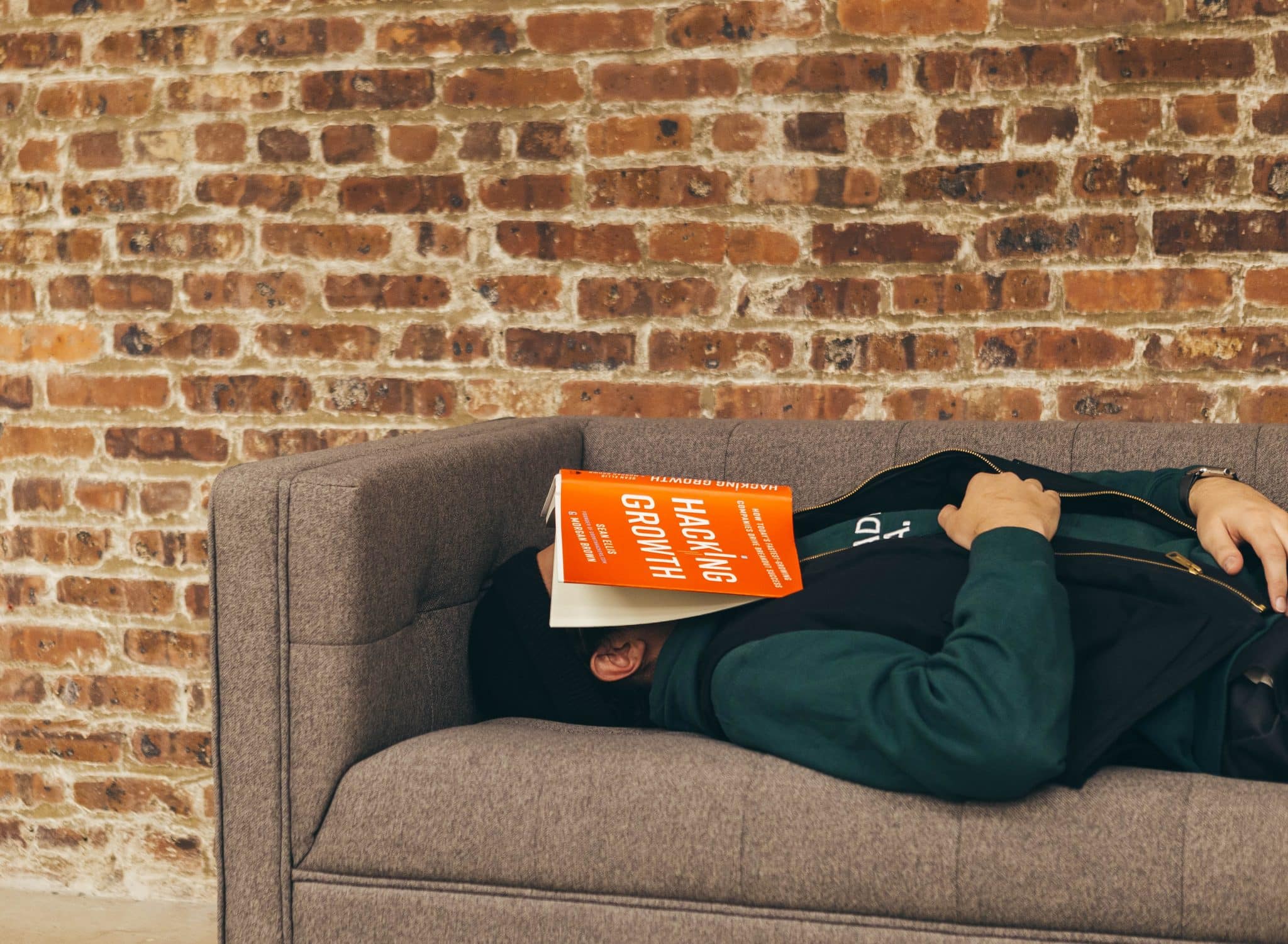 Man who has fallen asleep on the sofa with a book over his face