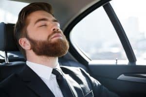 Business man sleeping in the back seat of a car