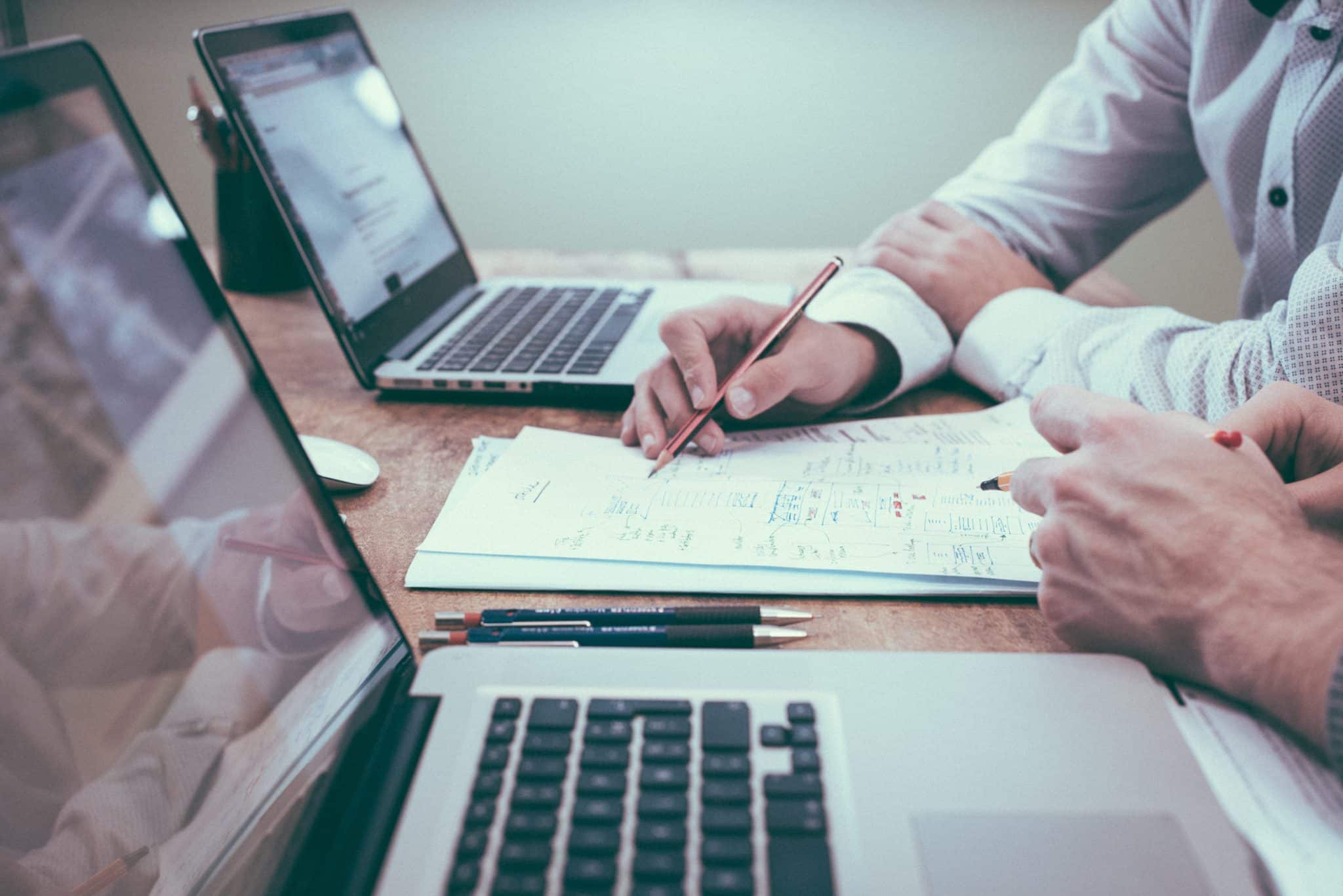 A photo of two people working side by side and taking notes.